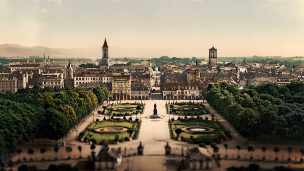 Historische kolorierte Stadtansicht von Karlsruhe mit Schlossgarten, Denkmal und Blick über die Dächer bis zu den Hügeln