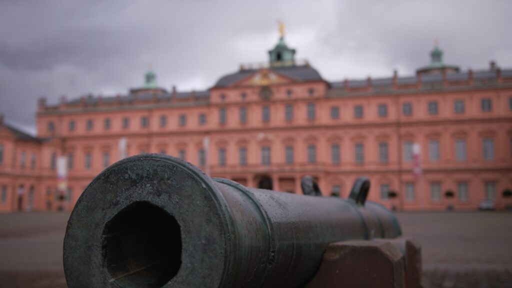 Altes Kanonenrohr aus Bronze vor der Fassade des Residenzschlosses Rastatt unter grauem Himmel