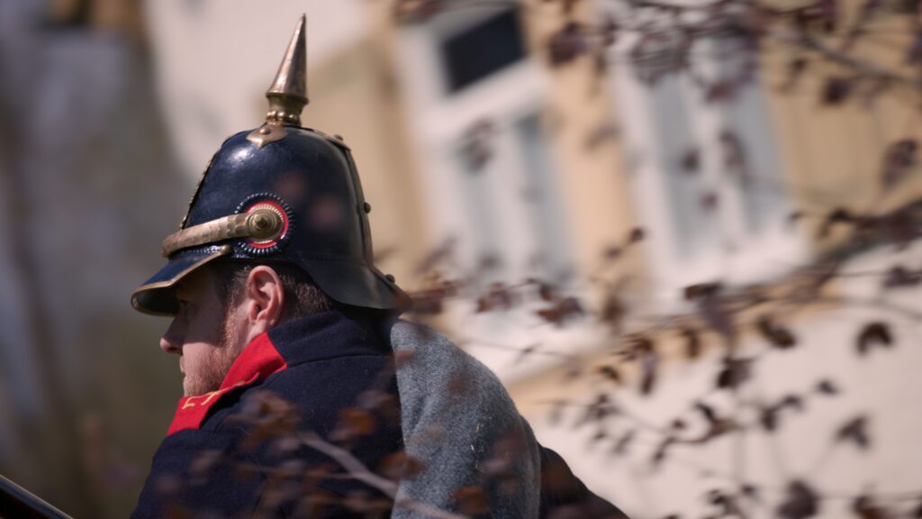 Darsteller eines preußischen Soldaten mit Pickelhaube und rotem Kragen im Profil